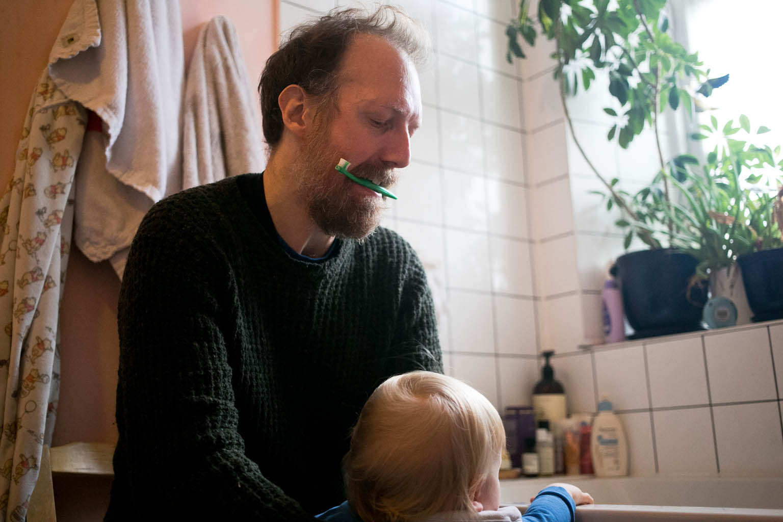 Father with baby toothbrush in teeth picking up son