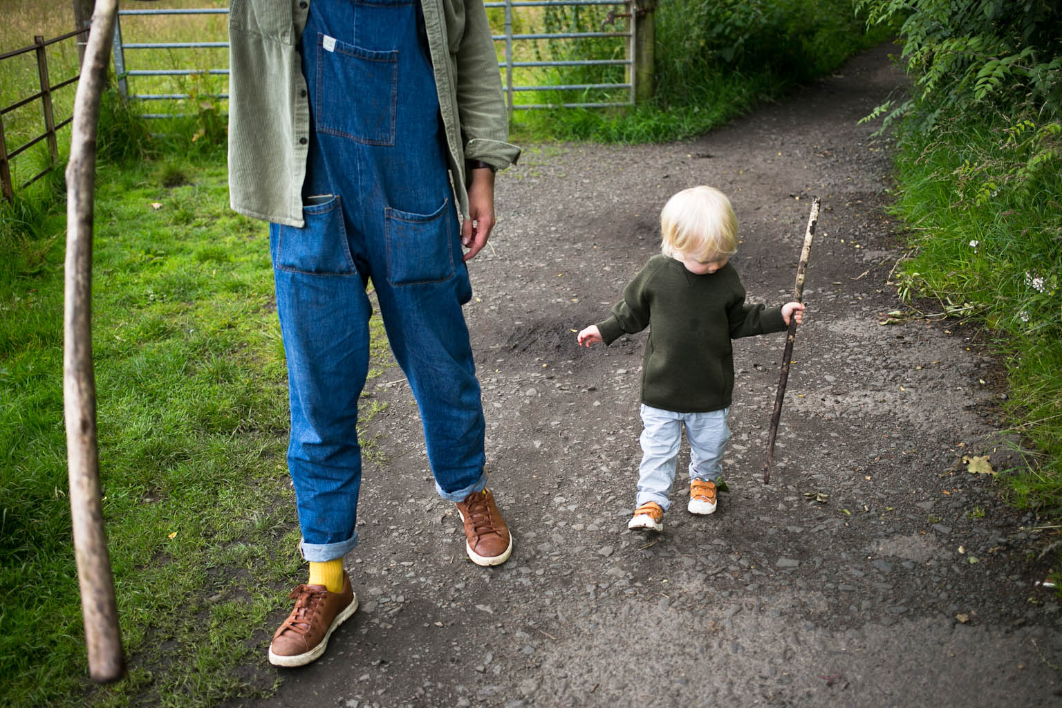 Young boy walking with father both carrying sticks
