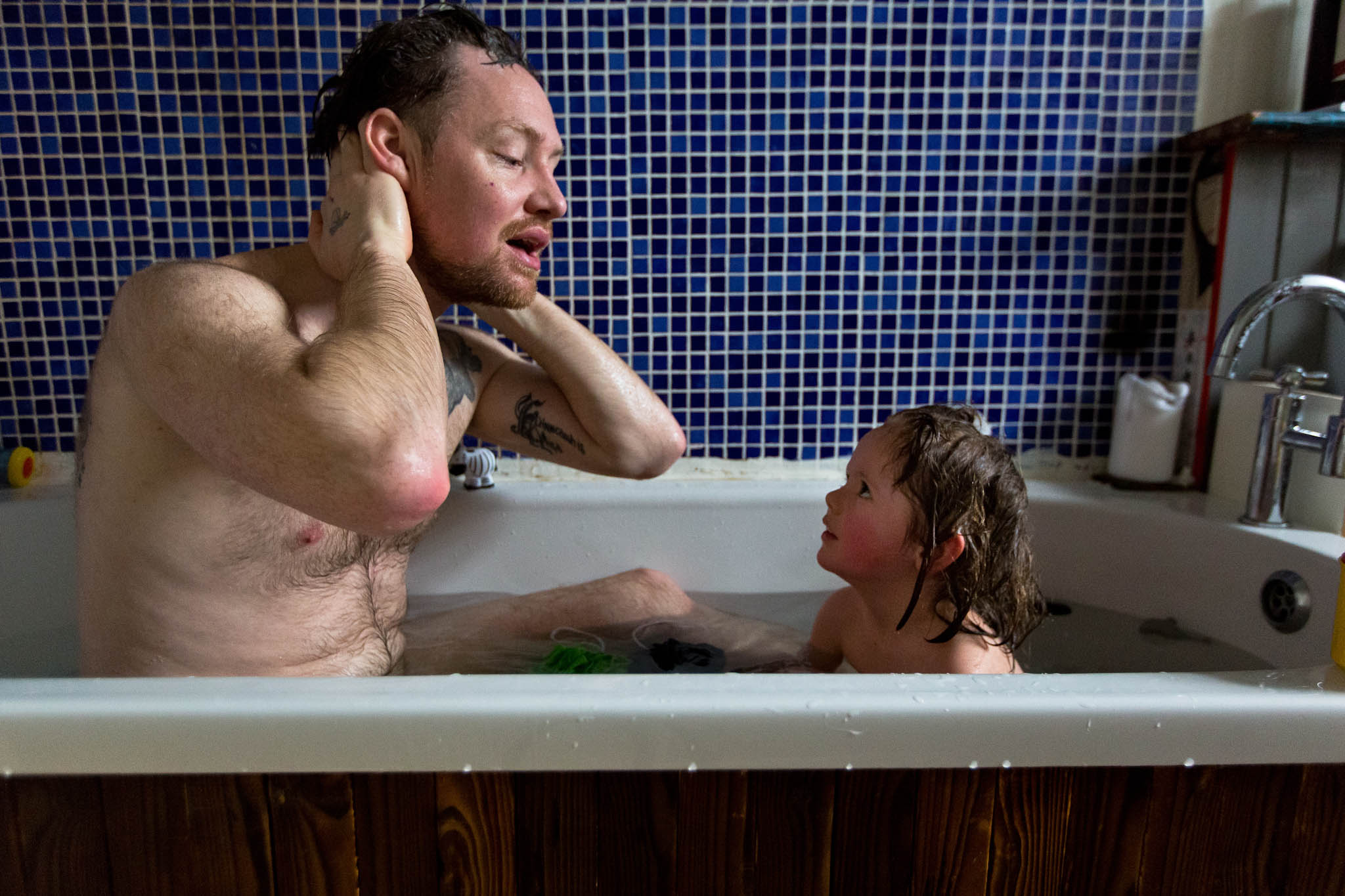 Father washing in the bath with baby daughter