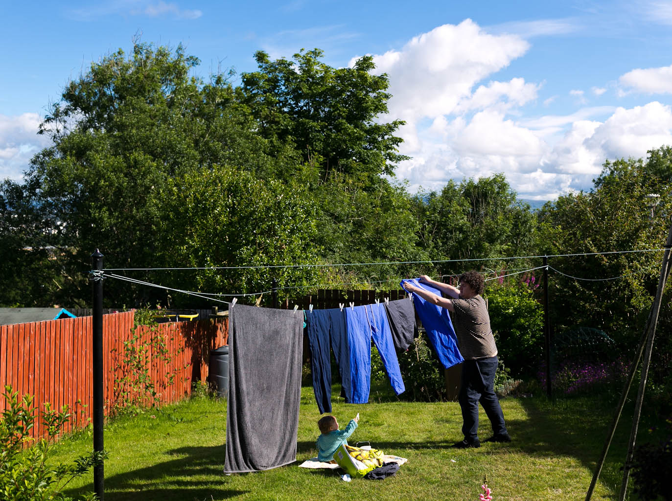Father hanging washing on line with baby daughter