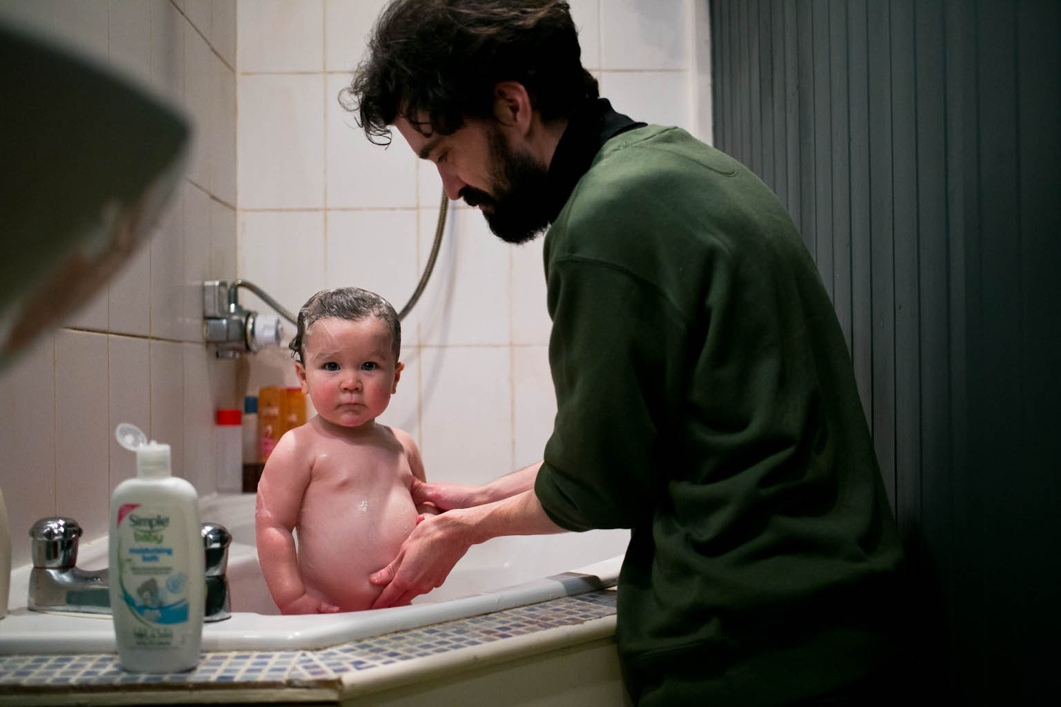 Father washing baby daughter's tummy in bath